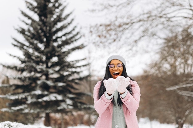 Portrait of happy positive girl African American young woman in glasses and gloves in winter park