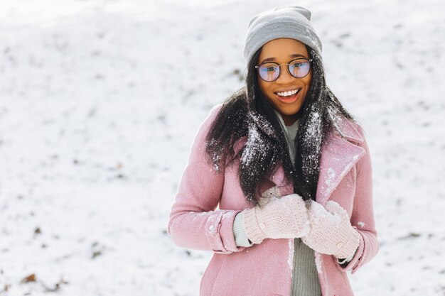 Portrait of happy positive girl Une jeune femme africaine en lunettes et gants sourit en hiver