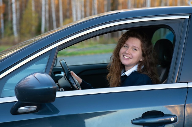 Portrait of happy positive girl young woman driver est assis dans sa voiture nouvelle automobile appréciant la conduite en s'amusant rire Joyful lady in auto looking at camera