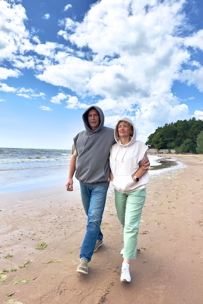 Portrait of happy senior couple âgé amoureux marchant sur une plage à l'été sourire rire s'amuser