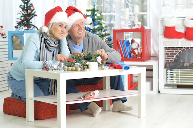 Portrait of happy senior couple in Santa hats se préparant pour Noël