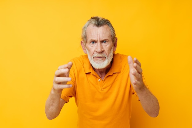 Portrait of happy senior man chemise jaune posant émotions fond jaune