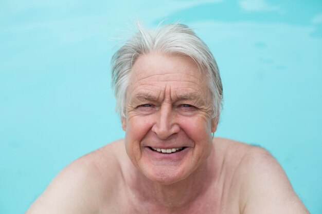 Portrait of happy senior man nager dans la piscine