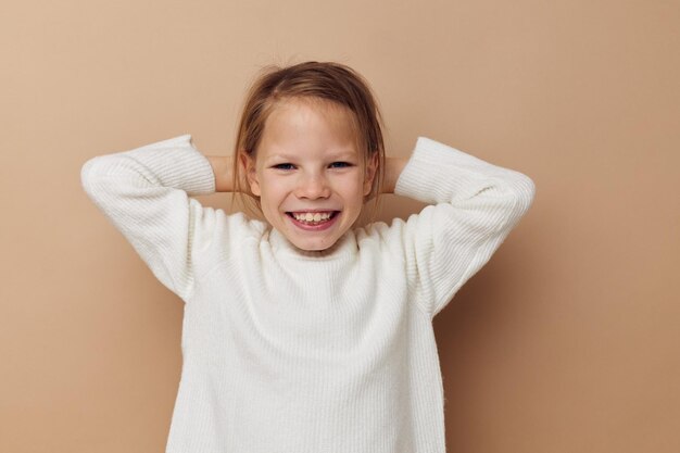 Portrait of happy smiling enfant fille en chandail blanc posant des gestes de la main