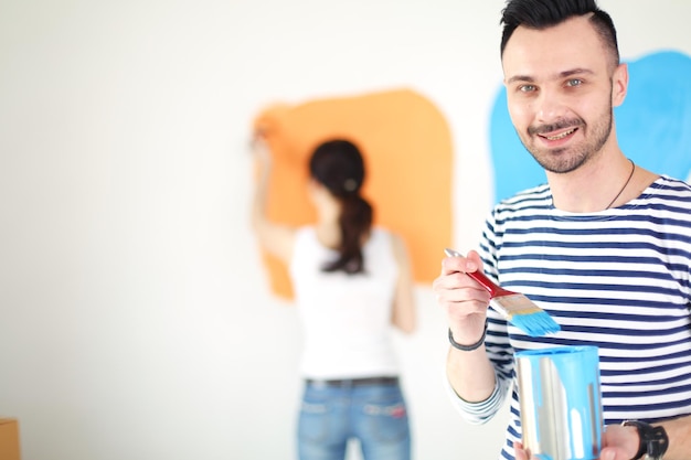 Portrait of happy smiling young couple peinture mur intérieur de nouvelle maison jeune couple