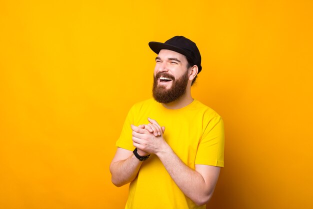 Portrait of happy smiling young man hipster barbu sur fond jaune