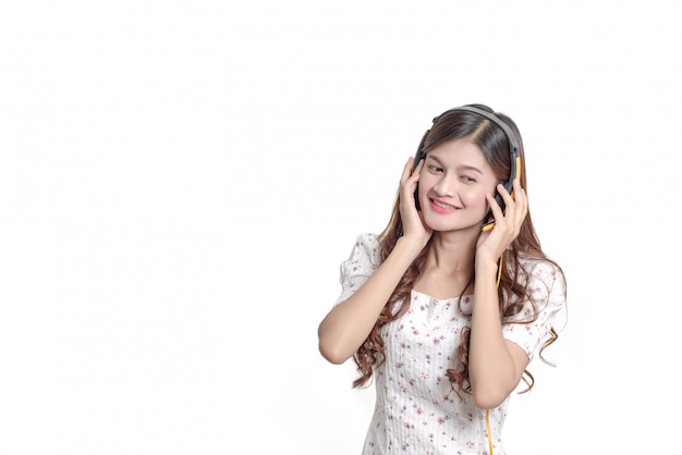 Portrait of happy young asian woman mettre des écouteurs écouter de la musique, belle fille thaïlandaise souriante sur mur blanc