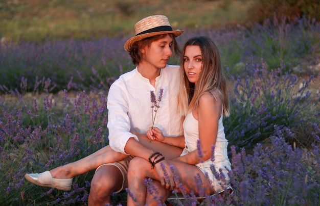 Portrait of happy young couple in love assis dans un champ de lavande