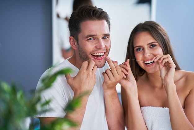 Portrait of happy young couple soie dentaire dents dans la salle de bain