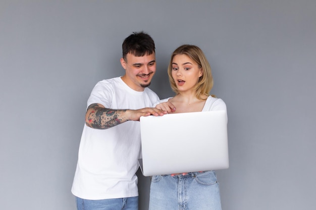 Portrait of happy young couple using laptop isolé sur fond gris