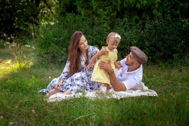 Portrait of happy young family joue avec leur petite fille au pré vert