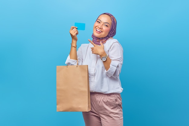 Portrait of happy young girl holding shopping bag et carte de crédit