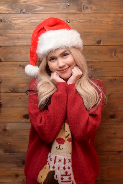 Portrait of happy young woman in santa claus hat sur fond de bois