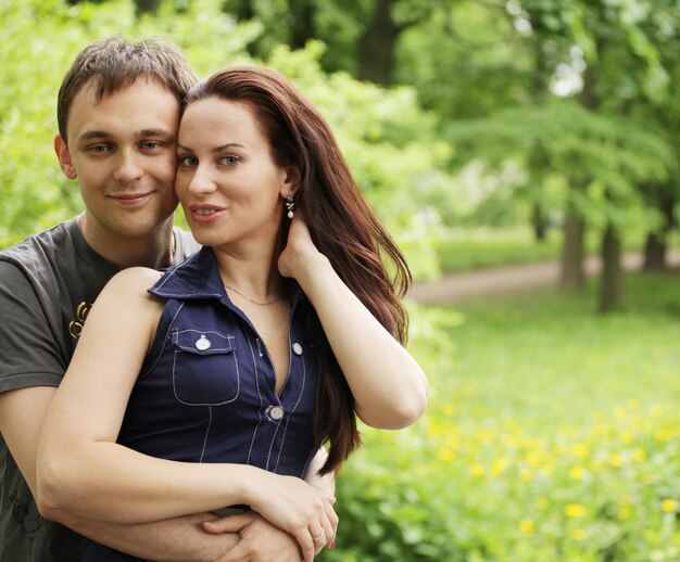 Portrait of love couple embracing outdoor in park looking happy