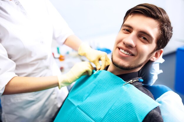 Portrait of male smile face L'inspection dentaire est donnée à Bel homme entouré de dentiste