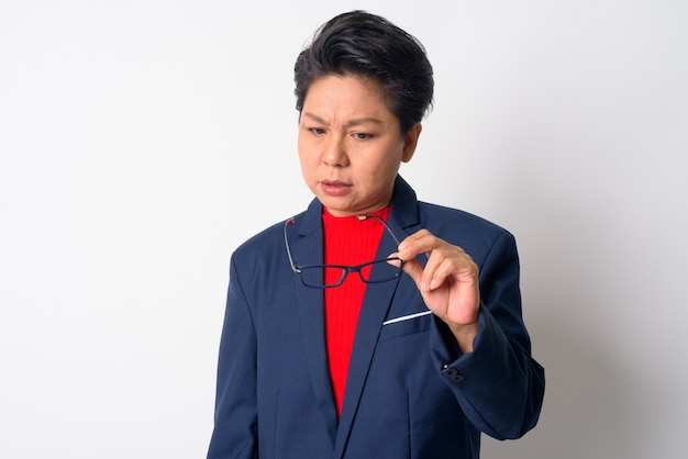 Portrait of mature asiatique garçon manqué businesswoman wearing suit contre le mur blanc