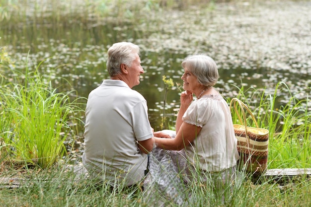 Portrait of nice young couple sitting by pond