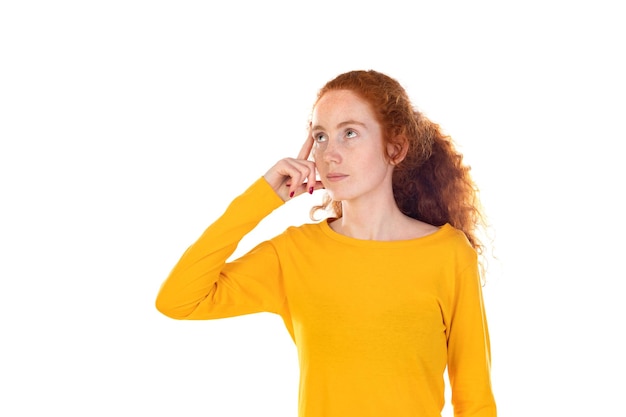 Portrait of pensive redhead girl wearing a yellow tshirt isolated on white background studio