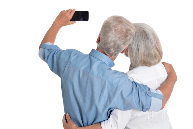 Portrait of senior couple prenant selfie sur fond blanc