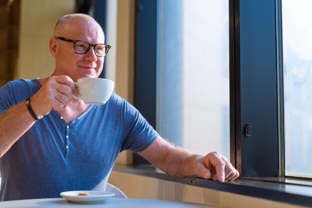 Portrait of senior handsome homme touriste scandinave se détendre à l'intérieur du café