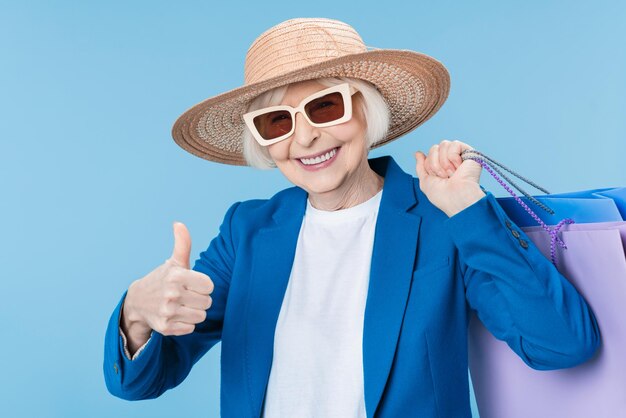 Portrait of senior lady with shopping bags and thumb up isolé sur fond blanc