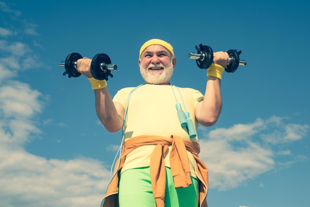 Portrait of senior man holding haltère senior man in health club senior man exerçant sur le ciel bleu ...