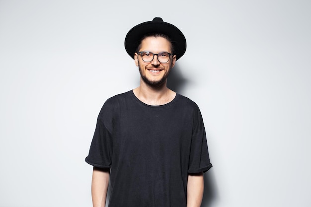 Portrait of a smiling attractive young man in black fedora hat and glasses