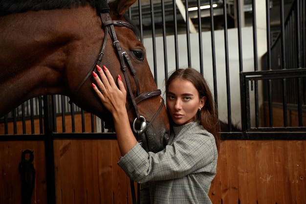 Portrait of smiling female jockey standing by horse in stable