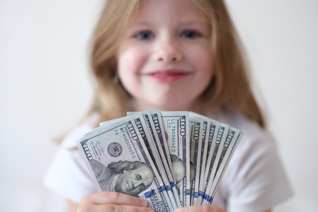 Portrait of smiling girl holding fan avec des dollars