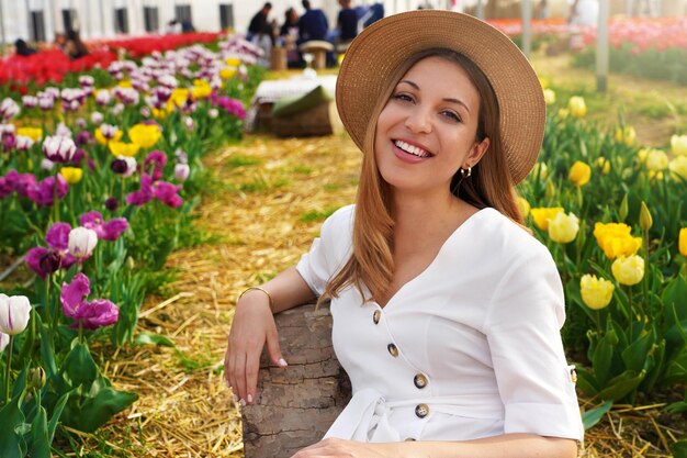 Portrait of smiling girl sitting détendu entre les champs de tulipes au printemps Looking at camera