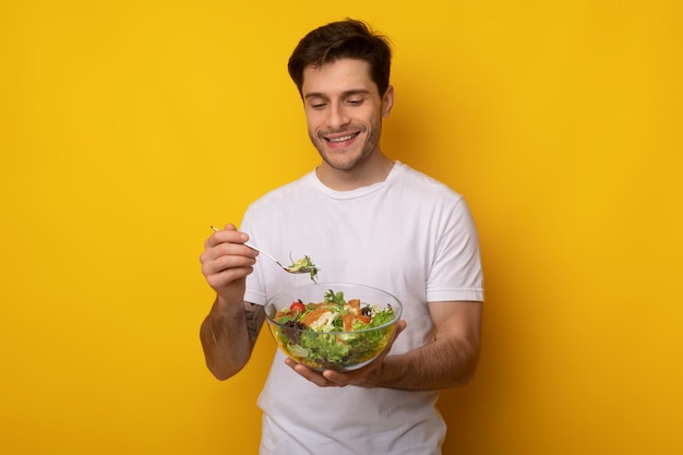 Portrait of smiling guy holding bowl avec salade