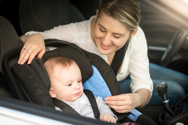 Portrait of smiling mother in car ayant son petit garçon dans le siège de sécurité