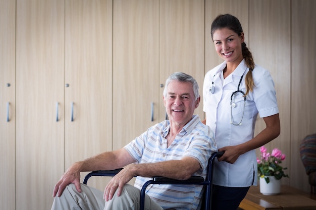 Portrait of smiling senior man and female doctor in living room