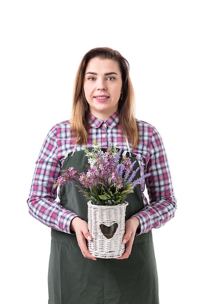 Portrait of smiling woman jardinier professionnel ou fleuriste en tablier tenant des fleurs dans un pot isolé sur fond blanc