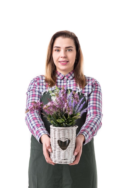 Portrait of smiling woman jardinier professionnel ou fleuriste en tablier tenant des fleurs dans un pot isolé sur fond blanc