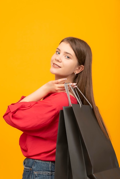 Portrait of smiling woman with big black shopping bags Femme après un bon shopping Fond jaune vif Cadre vertical