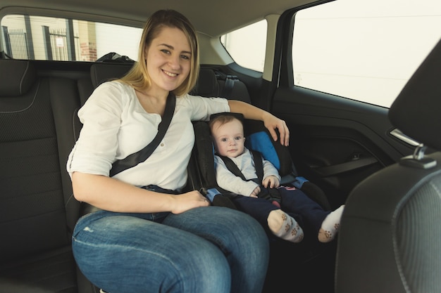 Portrait of smiling young mother and baby boy in car safety seat