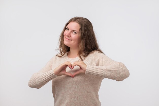 Portrait of smiling young woman with heart shape hand sign Prenez soin de votre santé
