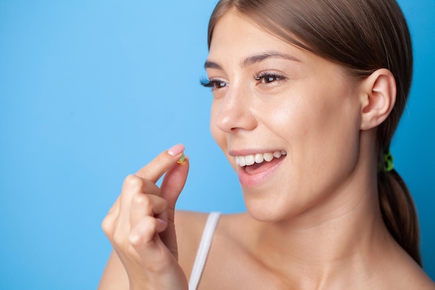 Portrait of smiling young woman with Omega 3 capsule d'huile de poisson