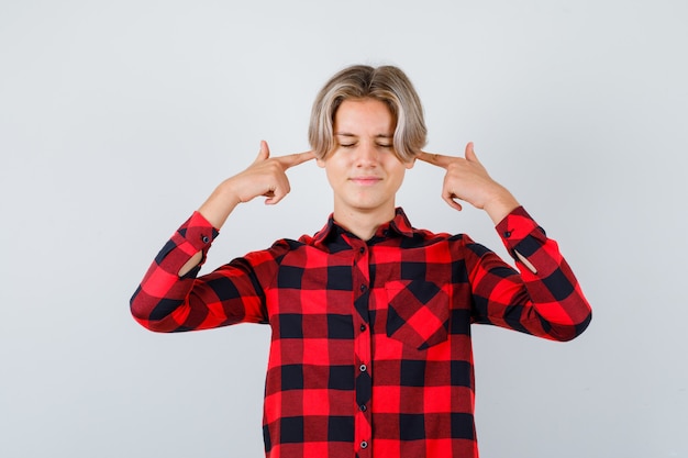 Photo portrait of teen blonde male brancher les oreilles avec les doigts en chemise décontractée et à la vue de face ennuyé