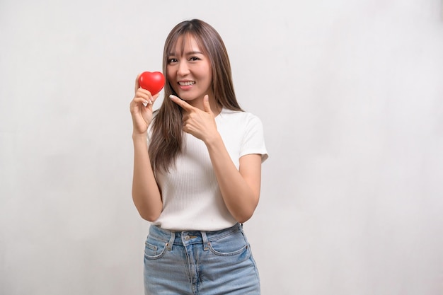 Portrait of young asian woman holding holding red heart shape over white background studio