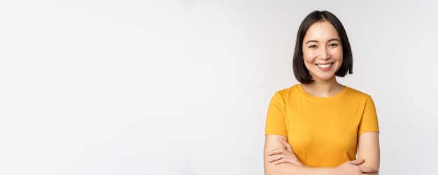 Portrait of young beautiful brunette asian girl smiling and looking happy bras croisés sur la poitrine standi