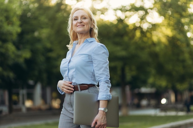 Portrait of a young businesswoman holding a laptop Happy senior woman office worker Femmes des années 50 Le concept de travail Freelance Success