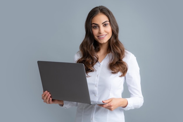 Portrait of young casual girl standing isolé sur fond gris à l'aide d'un ordinateur portable