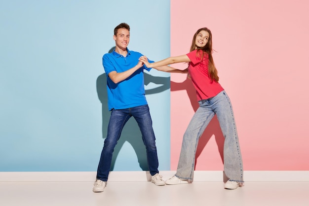 Portrait of young couple man and woman in casual clothes dancing isolé sur fond bluepink