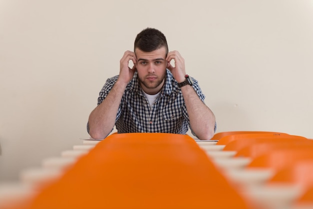 Portrait Of Young Male College Student With Book Sitting in Classroom Only