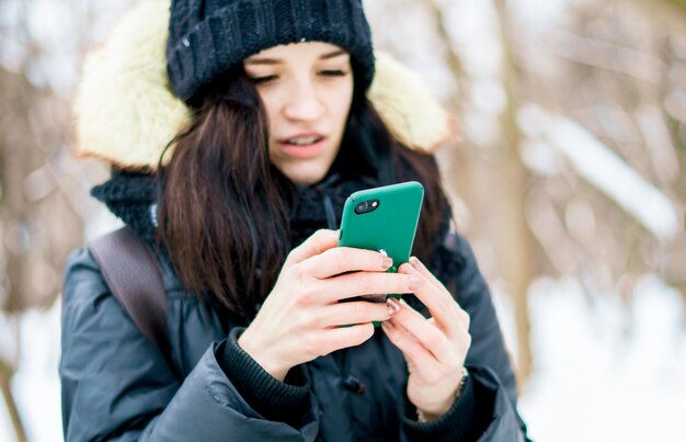 Portrait ofemale adolescent parler à l'aide de smartphone en plein air sur une journée d'hiver