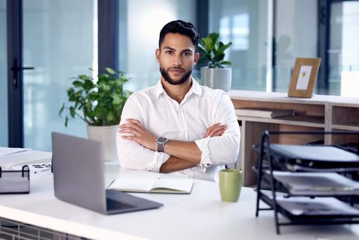 Photo portrait ordinateur portable et homme avec les bras croisés entreprise et employé dans un bureau moderne sérieux et succès de démarrage visage homme et entrepreneur avec une carrière pc et professionnel sur un lieu de travail