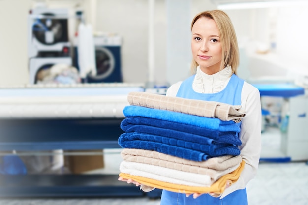 Portrait d'un ouvrier de blanchisserie sur le fond des vêtements sur des cintres dans le nettoyage à sec