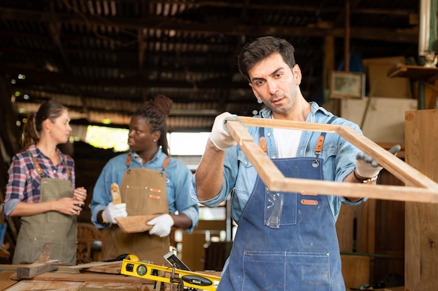 Portrait d'un ouvrier de charpentier debout devant un collègue dans l'atelier